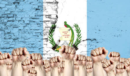 Raised fists of men against the background of the flag of Guatemala painted on the wall, the concept of popular unity and the opinion of the majority.の写真素材