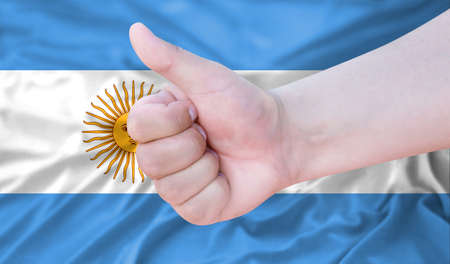 Hand makes a thumbs up sign on the background of the flag of Argentina. like, good, positiveの写真素材