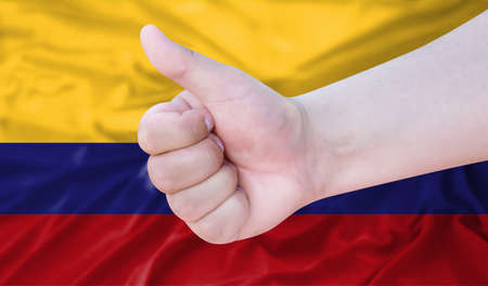 Hand makes a thumbs up sign on the background of the flag of Colombia. like, good, positiveの写真素材