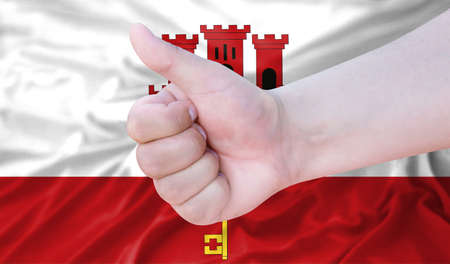 Hand makes a thumbs up sign on the background of the flag of Gibraltar. like, good, positiveの写真素材