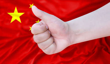 Hand makes a thumbs up sign on the background of the flag of China. like, good, positiveの写真素材