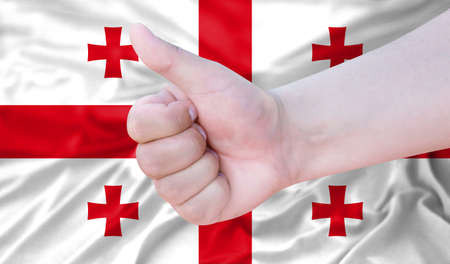 Hand makes a thumbs up sign on the background of the flag of Georgia. like, good, positiveの写真素材