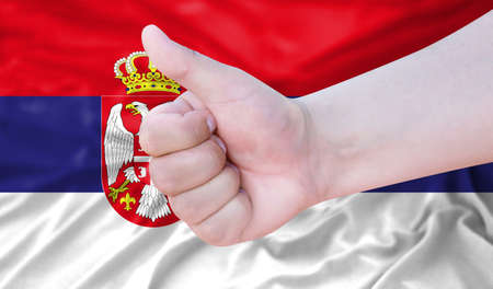 Hand makes a thumbs up sign on the background of the flag of Serbia. like, good, positiveの写真素材