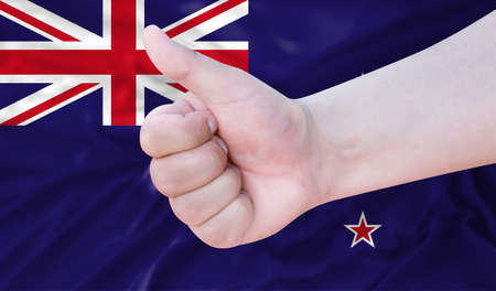 Hand makes a thumbs up sign on the background of the flag of New Zealand. like, good, positiveの写真素材