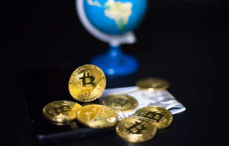 Cryptocurrency bitcoin close-up with american dollars, in the background the globe, the concept of...