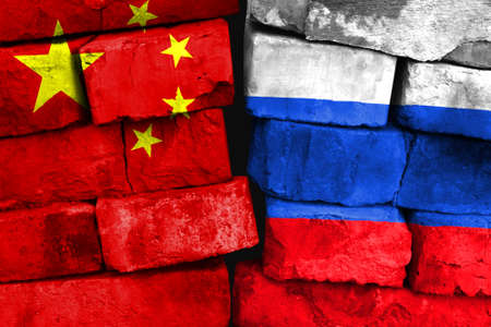 Concept of the relationship between China and Russia with two painted flags on a damaged brick wallの写真素材