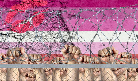 Raised fists against the background of the depicted flag of Lipstick lesbian behind barbed wire.の写真素材