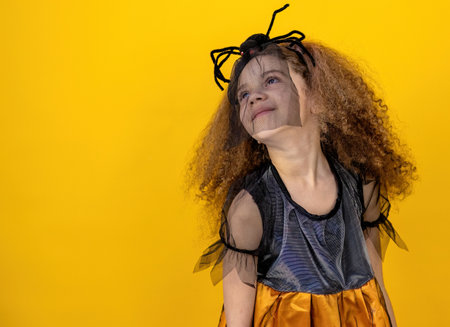 Little girl with curly hair in a dress on a yellow background.の写真素材