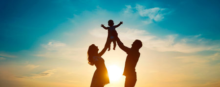 Dad and Mom raised a small child in their arms. Signs the family at sunset. People walk in nature. Side viewの素材