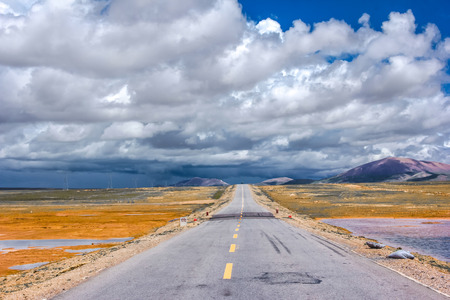 Asphalt road under blue sky with cloudsの写真素材
