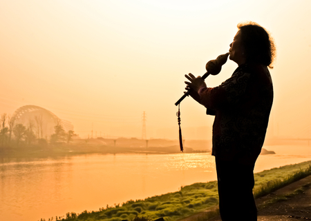 a man playing music instrument beside lakeのeditorial素材