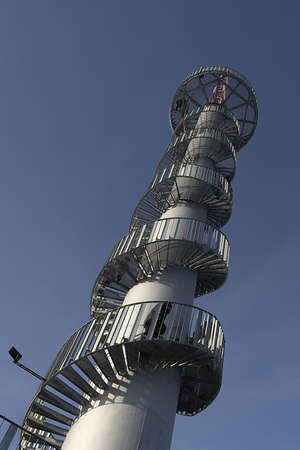 High lookout tower with spiral metal stairs against a beautiful blue skyの写真素材