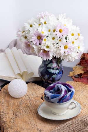 Bouquet of flowers in a jug with a cup of balls on a wooden background.の写真素材