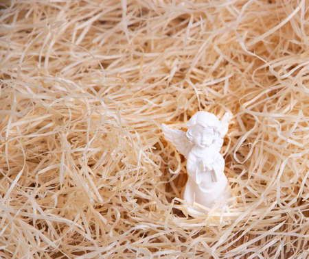 Little white angel on a background of straw in a minimalist presentation.の写真素材