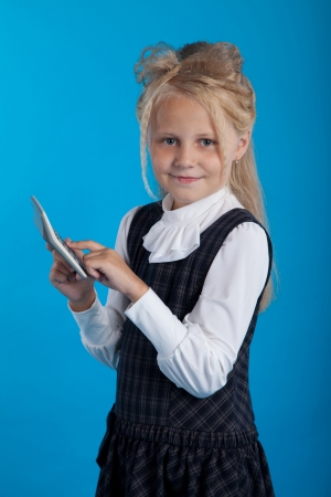 Schoolgirl considers on the calculator on a blue backgroundの写真素材