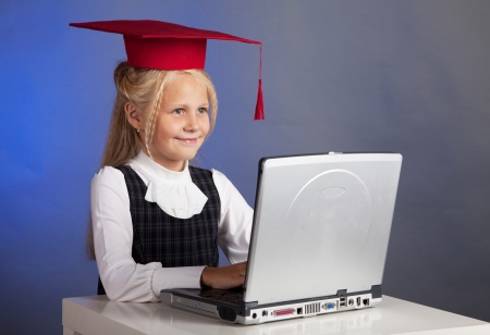 school girl in a red hat, working on a computerの写真素材