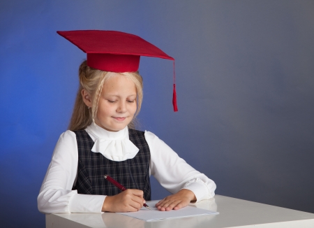 school girl in a red hat with a tassel writesの写真素材