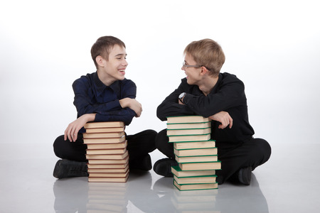 Two teenagers with piles of books on a white backgroundの写真素材