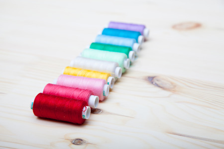 colorful spools of thread on a wooden background