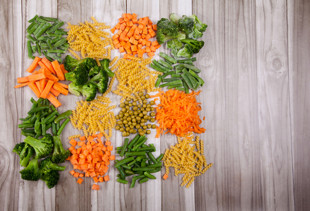 Carrots, broccoli, beans, green pea, paste
on a wooden tableの写真素材