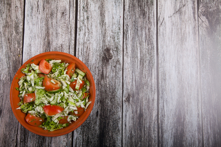 salad of tomatoes, cucumbers and cabbage is on a wooden tableの写真素材