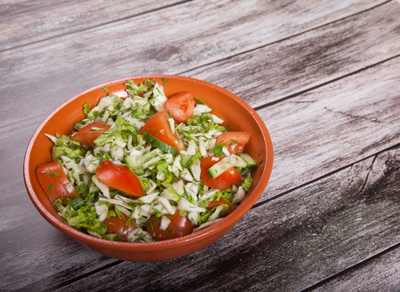 salad of tomatoes, cucumbers and cabbage is on a wooden tableの写真素材