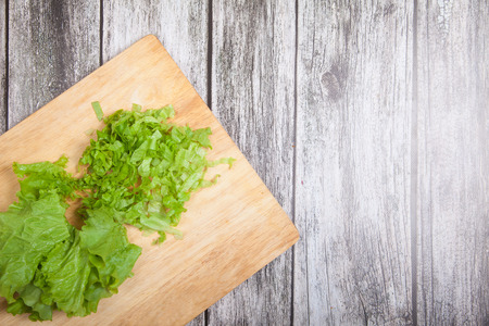 Cut fresh lettuce leaves lie on a cutting board on a wooden tableの写真素材