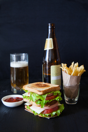 sandwich with beer and french fries on a black backgroundの写真素材