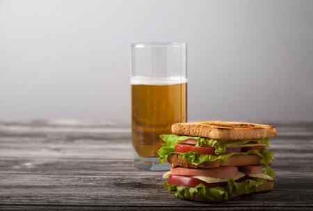 sandwich and a glass of beer on a wooden tableの写真素材