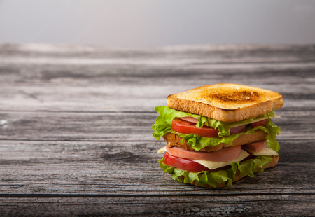 sandwich with meat, cheese and tomatoes on a wooden tableの写真素材
