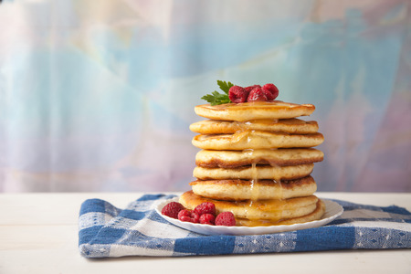 pancakes with raspberries on a white plate on a white tableの写真素材