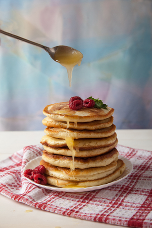 pancakes with raspberries on a white plate on a white tableの写真素材
