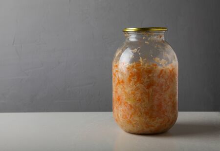 sauerkraut in a glass jar with a lid on a gray background