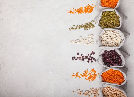 beans, lentils, peas, soybeans in bags and spilled on a white background. Keto diet. Natural...