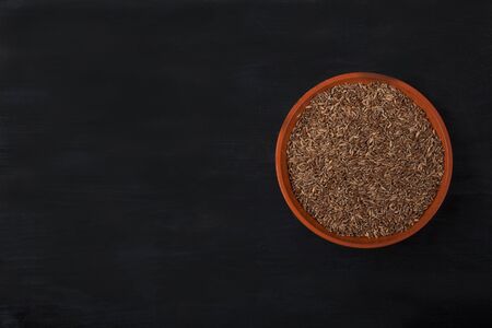 spelled groats lies in a clay cup on a black wooden background. superfoodの写真素材