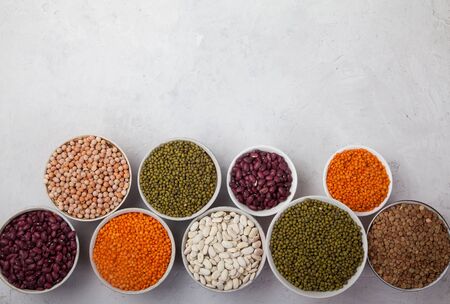 Red and white beans, green and red lentils, sunflower and pumpkin seeds poured in cups on a white background. superfoodの写真素材