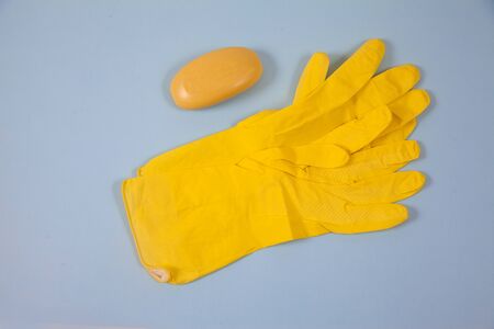 Yellow rubber gloves and Yellow soap lie on a blue background. Purity. Hygiene. Protection. topview