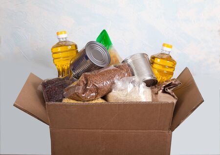 Food for donation in a box on a light background. Stock. Croup. social, social assistance