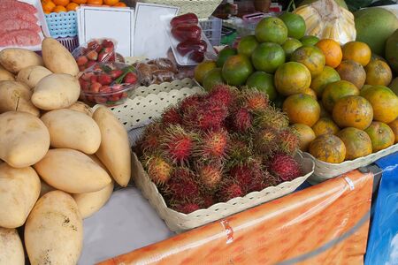 Fresh ripe rambutan, mango, tangerines are sold at a kiosk in Thailand. Asia. Travel. Healthy eating.の写真素材