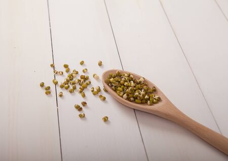 Sprouted mung bean in a wooden spoon on a white wooden background. Healthy eating.の写真素材