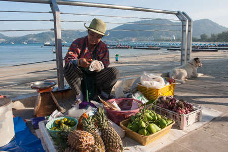 A woman sells fresh fruits and fish on Patong Beach in Thailand. January 28, 2019 Phuket. Asia. Journeyのeditorial素材