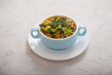 Bean soup with vegetables and cheese in a blue porcelain cup on a light concrete background. Vegetarian cuisineの写真素材