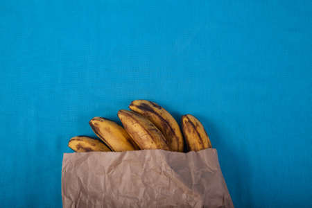 Ugly bananas in a paper bag on a blue background. Zero waste. Ecology.の写真素材