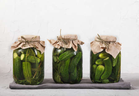 Big Jar with fermented cucumbers, salt in a wooden spoon and seasonings on a concrete background.の写真素材