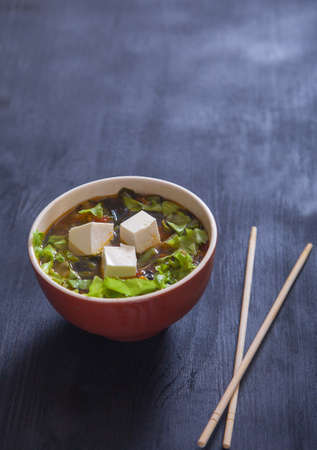 Japanese soup with tofu cheese and vegetables, chopsticks on black background. Copy spaesの写真素材