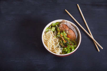 Japanese soup with vegetables and pasta and fish, chopsticks on a black background. Copy spaesの写真素材