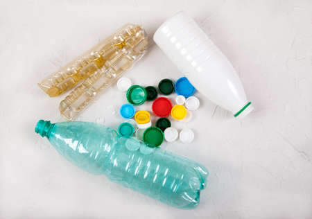 Garbage, waste from plastic bottles and caps on a concrete white background. Zero waste, ecology,...