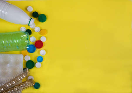 Waste, garbage from plastic bottles, cups, lids on a yellow background. Zero waste.