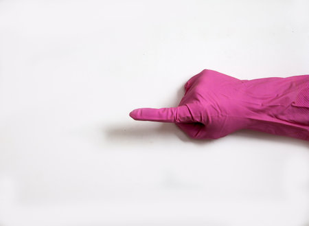 A hand in a pink rubber glove points a finger up on a white background. Medical. Purity. Hygiene. Close-up. Copy spaes.の写真素材