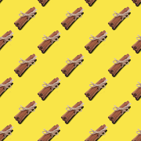 Pattern of cinnamon sticks tied with a string on a yellow background. Healthy food concept. Trending Color of the Year 2021. Illuminatingの写真素材